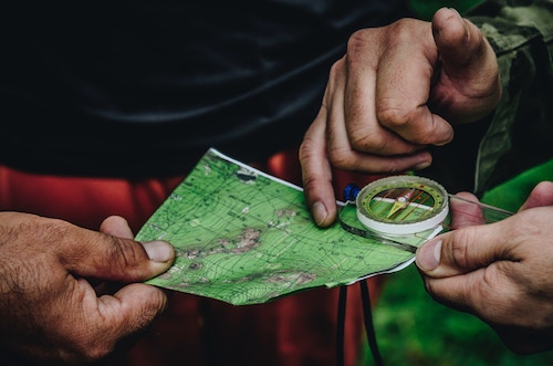 campers holding a compass on a green trail map